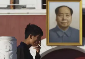  ?? NG HAN GUAN/THE ASSOCIATED PRESS ?? A young man smokes near a portrait of late Chinese leader Mao Zedong.