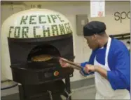  ?? AP PHOTO/TERESA CRAWFORD ?? In this May 23photo, inmate Marcus Clay, pulls pizza from oven at the Cook County Jail in Chicago. Inmates in the jail’s medium-security Division 11are now allowed to order pizzas made by participan­ts in the jail’s “Recipe for Change” program, which...