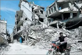  ?? HASSAN AMMAR/AP ?? A man rides Monday past destructio­n in Douma, site of a suspected poison gas attack.