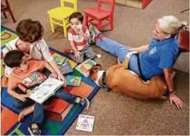  ?? Gary Fountain ?? Monique Caceres reads with her sons, David, 5, left, and Ben 3, near Judith Moore and her boxer Baker, at the Houston Public Library’s George B. Meyer Sr. Branch. “We need to come back every month,” Caceres told her boys.