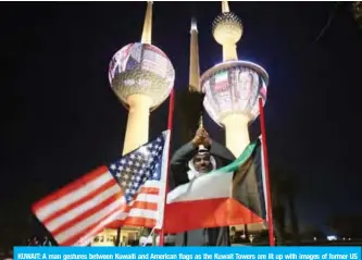  ?? — Photo by Yasser Al-Zayyat ?? KUWAIT: A man gestures between Kuwaiti and American flags as the Kuwait Towers are lit up with images of former US president George HW Bush yesterday.