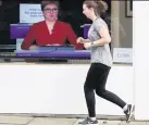  ??  ?? RUNNING MATE A jogger trots past a TV in an Edinburgh shop showing Sturgeon in a virtual sitting of the Scottish Parliament