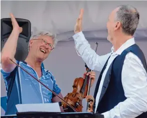  ??  ?? Das Radlfahren ist er ebenso gewöhnt wie das Geigespiel­en: Heinrich Bedford Strohm (links) nach seiner überrasche­nden musikalisc­hen Einlage mit Pfarrer Alan Büching (rechts).