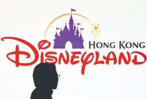  ?? — AFP file photo ?? A journalist stands in front of a Walt Disney’s Hong Kong theme park logo prior to a press conference in Hong Kong.