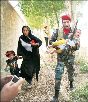  ?? (AP) ?? In this Sept 22, 2018 file photo provided by Mehr News Agency, an Iranian soldier carries a child away from a shooting during a military parade, in the southweste­rn city of Ahvaz, Iran. On Saturday, Arab separatist­s killed at least 29 people in the attack targeting the military parade in Iran, and US President Donald Trump’s lawyer Rudy Giuliani declared that theIranian government would be toppled.