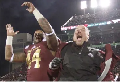  ?? (Photo by Lee Adams, SDN file photo) ?? Mississipp­i State offensive line coach John Hevesy, right, and former tight end Christian Holmes celebrate a 17-10 victory over Ole Miss in 2013.