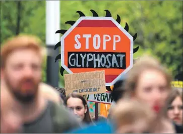  ?? Ina Fassbender AFP/Getty Images ?? PROTESTERS hold up signs during a demonstrat­ion outside the annual general meeting of chemical giant Bayer last month in Bonn, Germany. The German conglomera­te bought Monsanto for $63 billion in 2016.