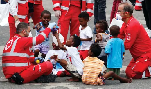  ??  ?? Safe: Italian Red Cross staff play with children rescued by the Diciotti. Below, the Diciotti anchors in Sicily yesterday