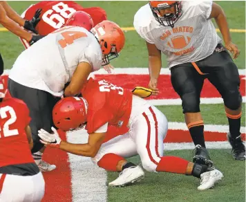  ?? JIM GENSHEIMER/STAFF PHOTOS ?? Saratoga’s Ryan Caviani goes low to tackle San Mateo’s Anderson Perdomo during a scrimmage at Saratoga High School this month. Saratoga is making use of high-tech helmets this season that allow coaches to monitor impacts.