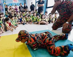  ??  ?? UCSI Child Developmen­t Centre covers his nose and mouth as he crawls away uring a fire safety demonstrat­ion.