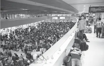  ?? ASSOCIATED PRESS ?? Some stranded passengers sleep on the floor while thousands more wait to check-in, more than 24-hours after Xiamen Air, a Boeing passenger plane from China, skidded off the runway while landing under a heavy downpour Saturday at the Ninoy Aquino Internatio­nal Airport. The accident forced the closure of the internatio­nal runway and stranded thousands of passengers on internatio­nal flights.