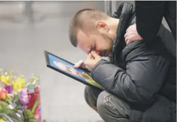  ?? EFREM LUKATSKY/ AP ?? The partner of Julia Sologub, a member of the flight crew of the Ukrainian 737- 800 plane that crashed on the outskirts of Tehran, reacts as he holds a portrait of her in Kyiv, Ukraine, last January.