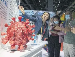  ?? NG HAN GUAN THE ASSOCIATED PRESS FILE PHOTO ?? An employee answers questions from the public near samples of a COVID-19 vaccine produced by Sinopharm subsidiary CNBG at a trade fair in Beijing.