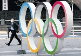  ??  ?? A man wearing a face mask walks past the Olympic rings in front of the Japan Olympics Museum in Tokyo.