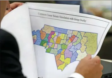  ?? AP PHOTO/GERRY BROOME ?? In this photo taken Wednesday, July 26, 2017 a lawmaker studies a district map during a joint select committee meeting on redistrict­ing in Raleigh, N.C. North Carolina’s nearly continuous legal battles this decade over how maps for state district boundaries are drawn don’t end with a landmark U.S. Supreme Court decision refusing to try to recalibrat­e boundaries to repair aggrieved political imbalances.