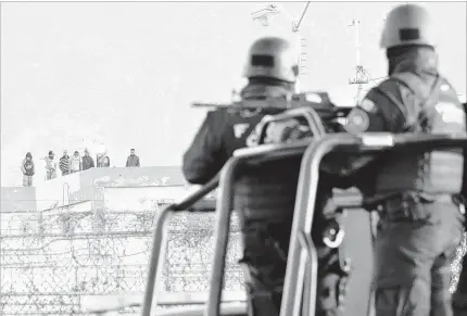  ?? EMILIO VAZQUEZ / ASSOCIATED PRESS ?? Inmates stand on the roof top of the Topo Chico prison Thursday a s police stand guard on the perimeters, af ter a riot broke out around midnight at the prison in Monterrey, Mexico. Of ficials said 49 inmates were killed and 12 injured when a brutal...