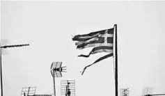  ??  ?? A frayed Greek national flag flutters among antennas atop a building in central Athens, Greece.The finance ministers of Germany and France said they were hopeful of a deal soon to move Greece’s bailout ahead, reiteratin­g that the IMF needs to be...