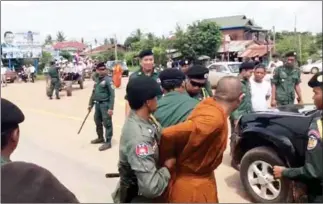  ?? FACEBOOK ?? A monk is taken in for questionin­g by police officials during an opposition rally on Friday in Oddar Meanchey province.