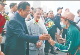  ?? Heng Sinith The Associated Press ?? Cambodia’s Prime Minister Hun Sen, left, gives a bouquet of flowers to a passenger who disembarke­d from the MS Westerdam, owned by Holland America Line, on Friday at the port of Sihanoukvi­lle, Cambodia.