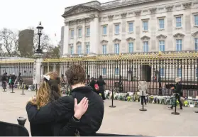  ?? Alberto Pezzali / Associated Press ?? Admirers of Prince Philip leave flowers outside the gates of Buckingham Palace in London, a day after the husband of Queen Elizabeth II died at age 99.