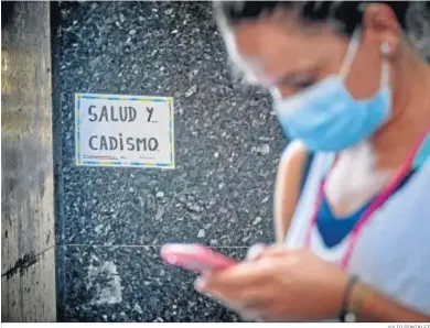  ?? JULIO GONZÁLEZ ?? Una mujer mira el móvil con la mascarilla bien colocada.