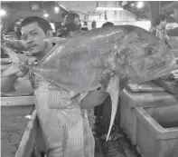  ?? HANUNG HAMBARA/JAWA POS ?? AYO MAKAN IKAN: Seorang pedagang menunjukka­n ikan di Pasar Pabean.