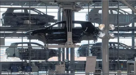  ?? Jens Meyer Associated Press ?? E-GOLF electric cars hang in a Volkswagen plant in Germany last year. Automakers’ transition to cleaner tech is further along overseas.