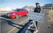  ?? NIC BOTHMA EPA ?? A JOBLESS man holds a rudimentar­y advertisin­g board offering his services at a traffic intersecti­on in Cape Town, in the desperate hope of getting work. |