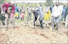  ?? ?? CANGO Director Thembinkos­i Dlaminbi (c) among those filling the grave of the late Katane.