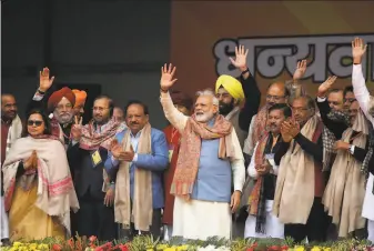  ?? Associated Press ?? Prime Minister Narendra Modi (center) greets supporters in New Delhi. Twentythre­e people have been killed nationwide since Parliament passed a citizenshi­p law this month.