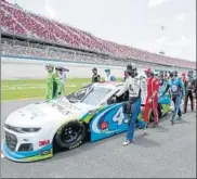  ?? FOTOS: AP/EFE ?? Los 39 pilotos y empleados de los conjuntos empujaron el coche de Bubba hasta la salida en un emotivo gesto para apoyar al único piloto afroameric­ano de la NASCAR