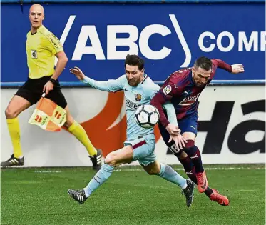  ?? — AP ?? Out of my way: Barcelona’s Lionel Messi (centre) vying for the ball with Eibar’s Anaitz Arbilla during the La Liga match at the Ipurua on Saturday.