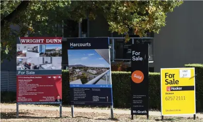  ?? Photograph: Lukas Coch/AAP ?? For sale signs outside an apartment block in Canberra. Economists say house prices will fall, at least in the short term, due to coronaviru­s restrictio­ns and massive retrenchme­nts.