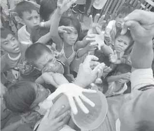  ?? PHOTO BY MIGUEL DE GUZMAN ?? Children mob a man handing out tickets for a free meal given by South Korean missionari­es at the Baseco compound in Manila on Tuesday.