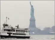  ?? ASSOCIATED PRESS ?? A Statue of Liberty and Ellis Island tour boat passes by the Statue of Liberty after dropping passengers off there, Monday, in New York, after resuming service early Monday during the government shutdown. The Statue of Liberty and Ellis Island opened...