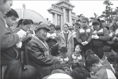  ?? SI WEI / FOR CHINA DAILY ?? Ma Ruying, a veteran who fought in the War of Resistance Against Japanese Aggression (1931-45), shares his memories about the war with students at a cemetery in Lianyungan­g, Jiangsu province, on April 5, Tomb Sweeping Day.