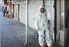  ?? LIAO PAN / CHINA NEWS SERVICE ?? Wearing protective clothing, a man walks on the street to pick up medication at a drug store in New York’s Chinatown.