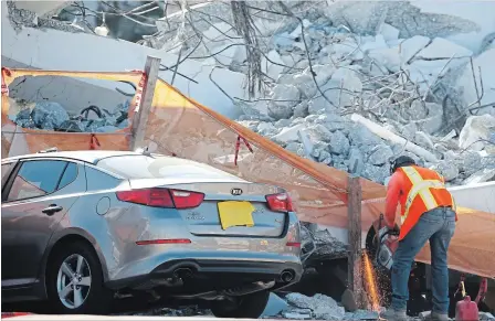  ?? WILFREDO LEE THE ASSOCIATED PRESS ?? A worker uses a saw next to a crushed car under a section of a collapsed pedestrian bridge Friday near Florida Internatio­nal University in Miami.