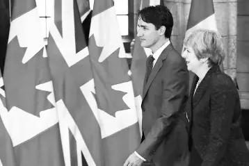  ??  ?? Canadian Prime Minister Justin Trudeau and British Prime Minister Theresa May walk by flags on Parliament Hill in Ottawa, Ontario, September 18. — AFP photo