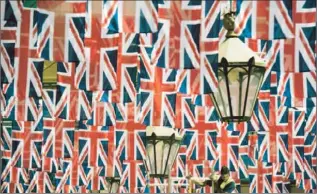  ?? Adrian Dennis Afp/getty Images ?? A MAN WORKS in a sea of British flags installed in the Covent Garden area of London as part of the Diamond Jubliee celebratio­ns marking Queen Elizabeth II’s 60 years on the throne.