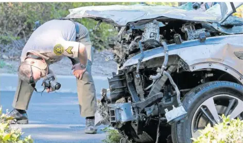  ?? FOTO: CHIU/AP ?? Ein Polizist fotografie­rt den vollkommen demolierte­n Wagen von Golf-Superstar Tiger Woods.