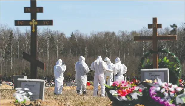  ?? Anton
Vaganov
/ reuters ?? Grave diggers wearing personal protective equipment gather Tuesday after burying a coronaviru­s disease victim
in the special purpose section of a graveyard on the outskirts of Saint Petersburg, Russia.