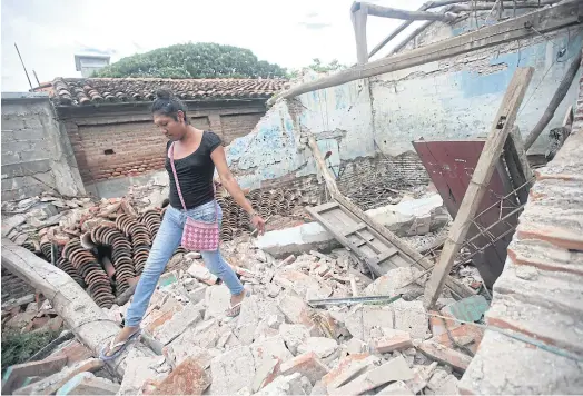  ??  ?? IN PIECES: Peregrina, 26, an indigenous Zapotec transgende­r woman, walks over debris left by the 8.1-magnitude earthquake.