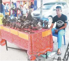  ??  ?? An entreprene­ur from Kuching at his stall selling bronze decorative items.