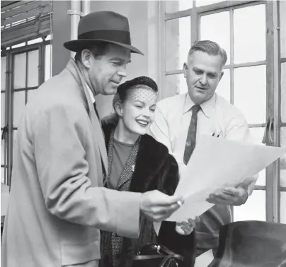  ?? THE COMMERCIAL APPEAL ?? A snow-enforced delay on Jan. 23, 1956, at Municipal Airport gave Hollywood star Fred Macmurray, left, and his wife, June Haver, a former Memphian, the chance to check weather reports with James C. Hicks, an aviation forecaster.