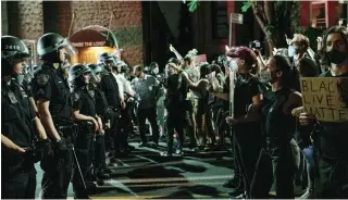  ?? SCOTT HEINS GETTY IMAGES ?? Protesters face off with police officers after violating a curfew in New York City on Thursday night.
