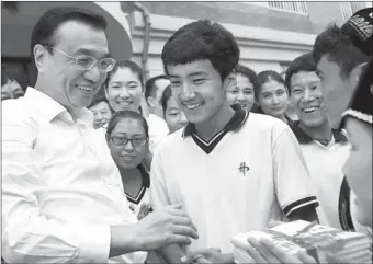  ?? ZOU HONG / CHINA DAILY ?? Premier Li Keqiang talks with Xinjiang students at Dalian No 20 Senior High School in Liaoning province on Monday, one day before Teachers’ Day.