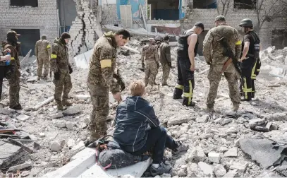  ?? Picture: AFP ?? DEATH WATCH. Yarvoslava, 51, who believes her husband is under the debris, waits as soldiers and members of a rescue team clear the scene after an abandoned school was shelled in Sydorove, Ukraine.