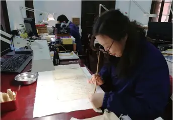  ??  ?? Yan Jingshu works on a handwritte­n genealogy book.