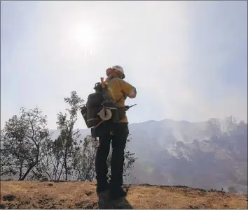  ?? Francine Orr Los Angeles Times ?? KRISTIAN LITZ of the L.A. County Fire Department helps extinguish a brush fire that was spotted early Friday in Griffith Park. Aided by a lack of wind, fire crews had put out most visible flames by late morning.